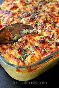 a casserole dish with cheese and spinach being scooped from the casserole