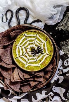 a bowl of guacamole and tortilla chips on a black and white cloth