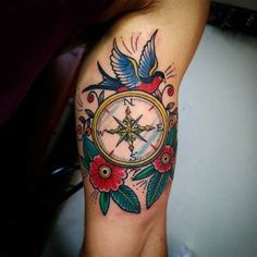 a tattoo on the leg of a woman with a compass and flowers around it,