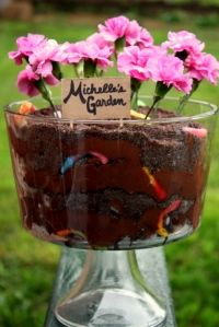 there is a small cake with flowers in it on the table and a sign that says mother's garden