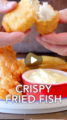 two hands holding food over a plate with fries and dip