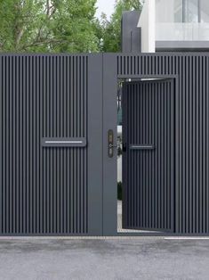 an entrance to a modern house with black metal doors and vertical slats on the sides