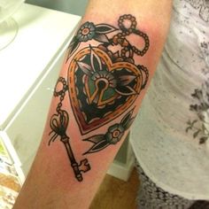 a person with a tattoo on their arm holding a key and heart in the middle