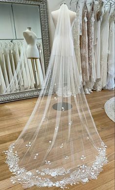 a wedding veil on display in front of a dress rack and mannequins