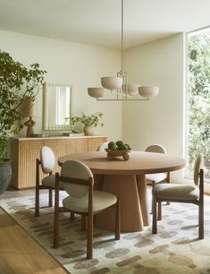 a dining room table with chairs and a potted plant in the corner next to it