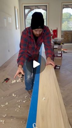 a man is working on a piece of wood in the living room with blue tape