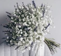 a bouquet of white flowers sitting on top of a bed next to a curtained wall