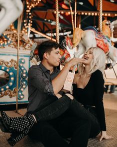 a man and woman sitting on the ground near a carousel