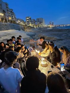 a group of people sitting around a table with cake and candles in front of them