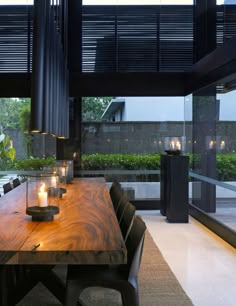 a wooden table with candles on it in front of a large glass window that looks out onto the backyard