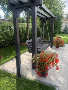 a wooden bench sitting on top of a cement ground next to flowers and trees in the background