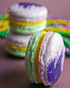 three colorful macaroons sitting next to each other on top of a purple table