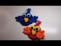 two crocheted birds sitting on top of a white table next to each other