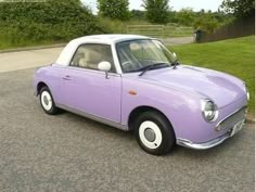 an old purple car is parked on the street