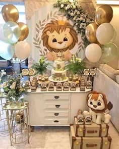 a table topped with lots of cake and balloons next to a lion head on top of a dresser