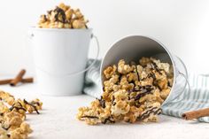 a bucket full of chocolate covered popcorn next to a cup with cinnamon sticks sticking out of it