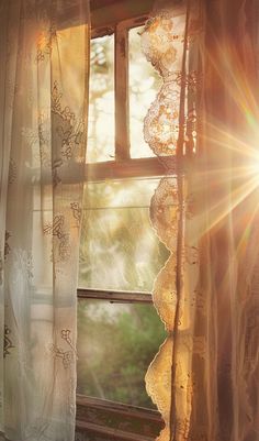 the sun shines through an open window with lace on it and curtains in front