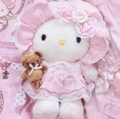 a hello kitty stuffed animal with a teddy bear in it's lap on a pink blanket