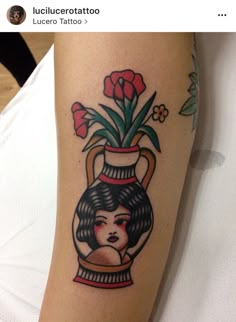 a woman's tattoo on the arm with flowers in a vase behind her head