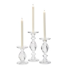 three clear glass candlesticks with one candle in the middle