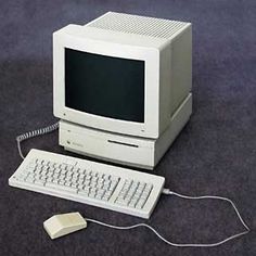 an old apple computer sitting on the floor next to a mouse and keyboard with wires running through it