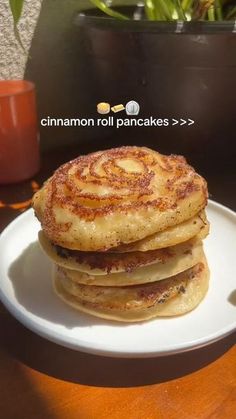 a stack of pancakes sitting on top of a white plate next to a potted plant