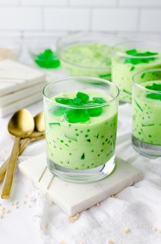 three glasses filled with green pudding on top of a table