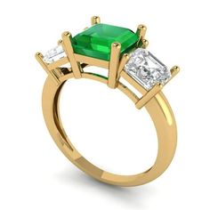 an emerald and diamond three stone ring with two diamonds on each side, set in yellow gold