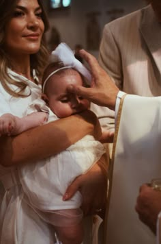 a woman holding a baby in her arms while wearing a priest's robe and hat