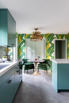 a kitchen with green and yellow wallpaper next to a dining room table surrounded by chairs