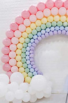 a rainbow balloon arch with white and pink balloons