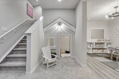 a white chair sitting in the middle of a hallway next to a stair case and table