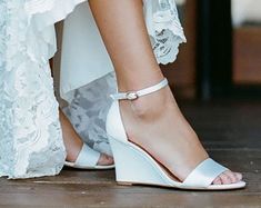 a close up of a woman's white wedged sandals on her wedding day