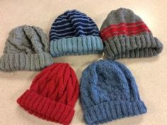 six knitted hats laid out in a circle on a counter top with one red, one blue and one gray