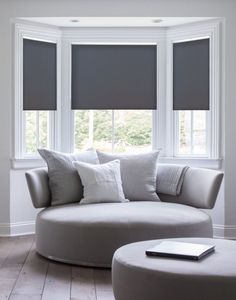 a living room filled with furniture and windows covered in roman blind shades on the windowsill