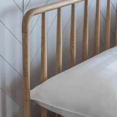 a close up of a wooden bed frame with a white pillow on the top and bottom