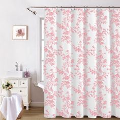 a pink and white shower curtain with flowers on it in a bathroom next to a window