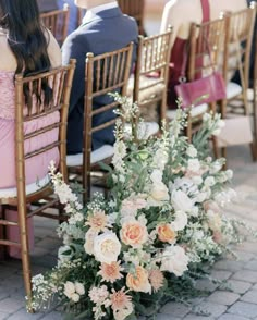 the bride and groom are sitting on their wedding day in chairs with floral centerpieces