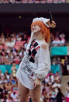 a woman with orange hair and white shirt on holding a tennis racquet in her hand