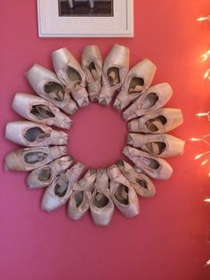 a wreath made out of ballet shoes hangs on the wall next to a framed photograph