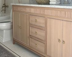 a white toilet sitting next to a wooden cabinet