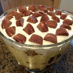 there is a dessert in the glass bowl on the counter with white frosting and chocolate pieces