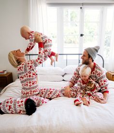 a man, woman and child in matching christmas pajamas on a bed