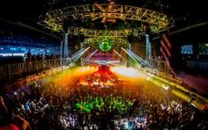 a large group of people at a concert in the middle of an arena with bright lights