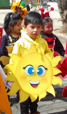 children in costumes are walking down the street with sun shaped paper plates on their heads