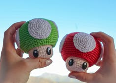 two crocheted mushrooms are held up in front of the camera with their eyes closed