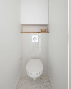 a white toilet sitting inside of a bathroom next to a wall mounted cabinet above it