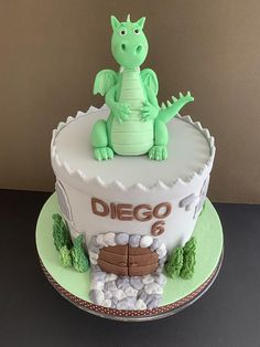 a birthday cake with a green dragon sitting on top of it's head and the words diego 6 written in white frosting