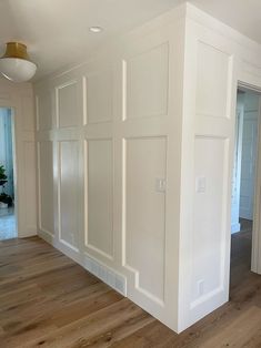 an empty room with white walls and wood floors