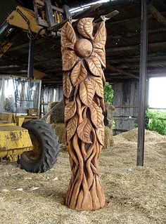 a large wooden sculpture sitting on top of a pile of hay next to a tractor